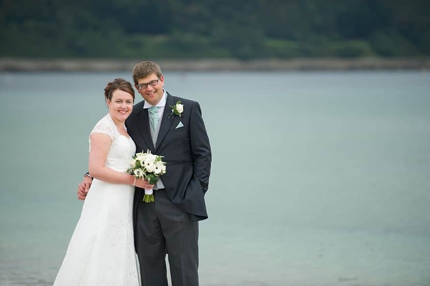 Bride and groom in love on the beach in falmouth over looking pendennis castle